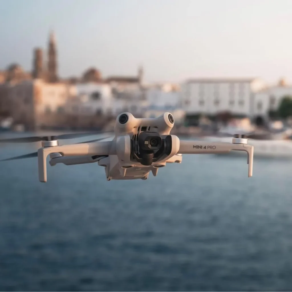 DJI Mini 4 Pro en vol stationnaire au-dessus de l'eau au coucher du soleil